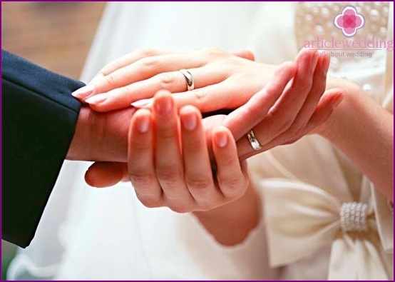 Wedding rings on the fingers of the newlyweds.